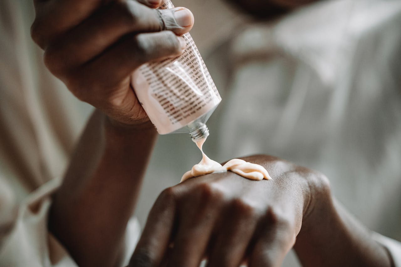 A close-up of hands applying skin care cream from a tube, emphasizing daily skincare routine.