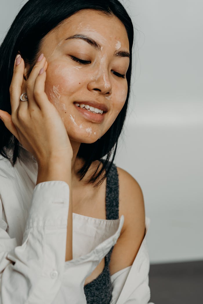 A woman applying skincare cream in a studio, showcasing beauty and self-care.