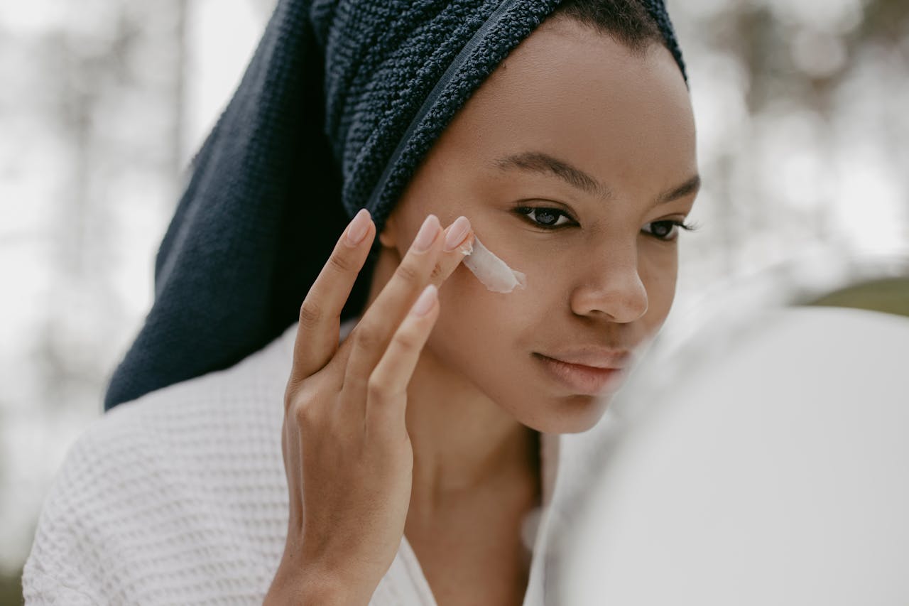 Woman gently applying facial cream in skincare routine, focusing on healthy skin.